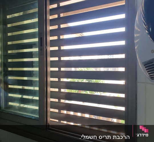 חלון הזזה מאלומיניום כהה עם תריס מותקן בקיר אריחים